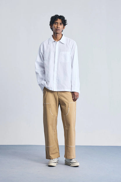 Person wearing a white shirt and beige pants on a plain background